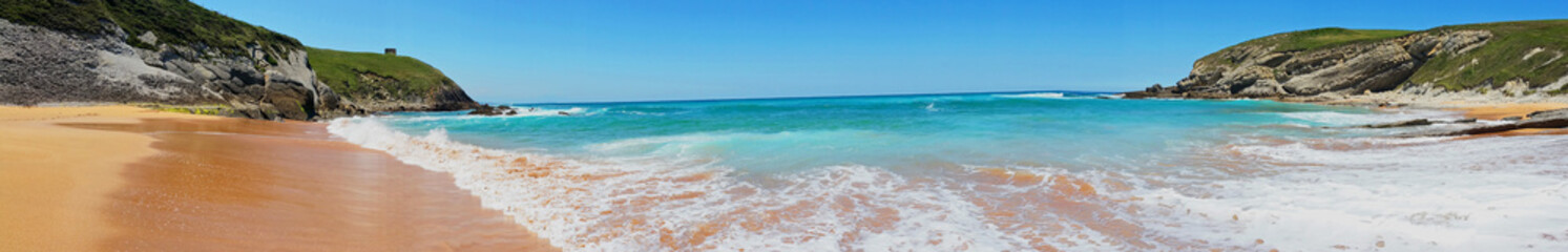 Beach with beautiful waves and blue sky, landscape. North Spain. Panoramic photo
