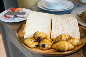 close up, pile of sliced wheat bread and french croissant in the wooden dish on the table for breakfast.