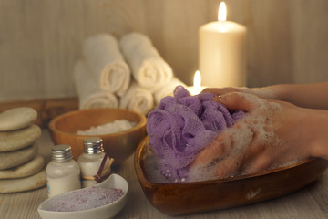 Obraz na płótnie Canvas Hands with a washcloth in soapy water on a background of a set for spa procedures