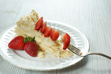 A piece of cake Napoleon on a plate with strawberries