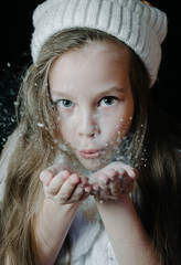 girl blowing on the palm of the hand with snow