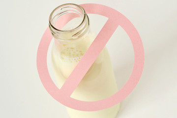 Glass bottle of milk with restriction sign - Lactose intolerance concept - obrazy, fototapety, plakaty