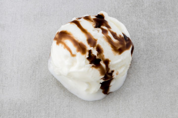  ice cream ball with chocolate sauce on gray background, top view