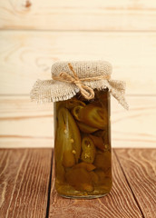 Jar of pickled green jalapeno peppers on table