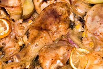 Chicken legs with potatoes  are fried in a pan with sauce closeup