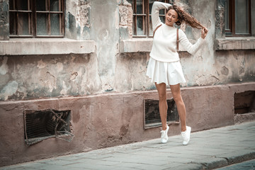 Funny smiling young stylish woman standing outdoor, summer, textured wall