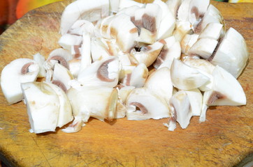 
Mushrooms champignons cut into small pieces lie on the board.