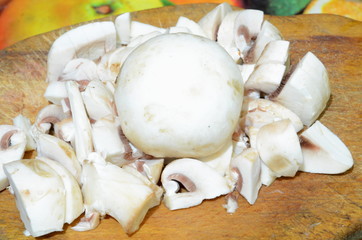 
Sliced ​​and whole mushroom mushroom lie on the cutting board before cooking.