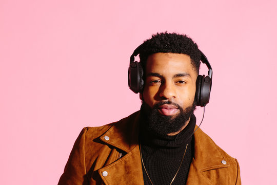 Cool African American man with beard, isolated on pink studio background