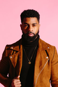 Simple portrait of a cool African American man with beard, isolated on pink studio background