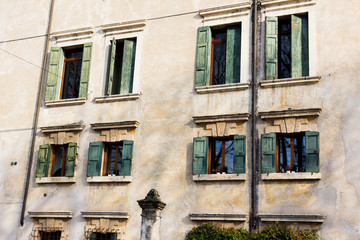 Fototapeta na wymiar Vintage house facade with windows and shutters. Italy.