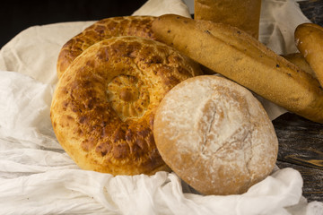 Conceptual still life art photography of a different kinds of bread wrapped in white cloth on an ancient wooden table.