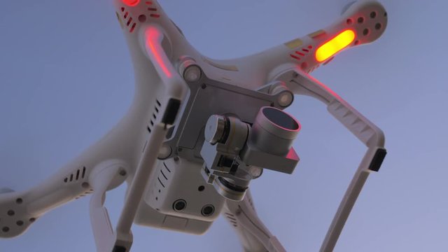 Low angle close-up shot of flying copter with attached ND filter. Shot against clear evening sky, drone lights blinking