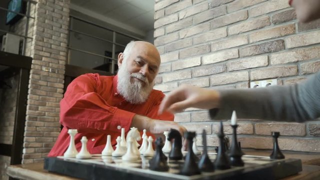 Senior man play chess with granddaughter at home