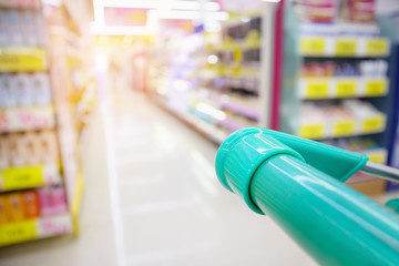 shopping cart with abstract blur supermarket discount store product shelves interior defocused background