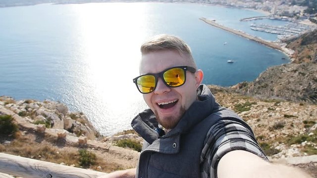 Happy man hiker tourist selfie picture on mountain near sea