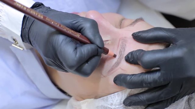 Microblading. Young girl doing the procedure of eyebrow coloring at the spa salon