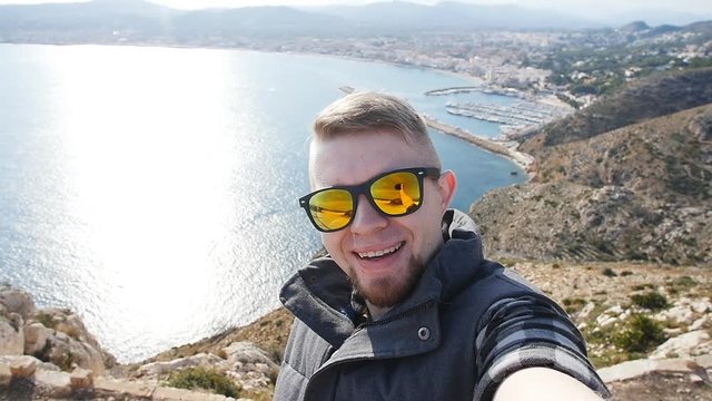Happy man hiker tourist selfie picture on mountain near sea