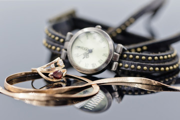 Elegant gold ring and chain lie on the background of women's watches