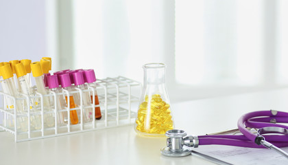 closeup of the desk of a doctors office with a stethoscope in the foreground and a bottle with pills in the background