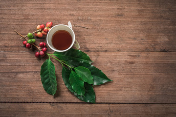 Coffee beans with real coffee fruits and leaves on wooden table