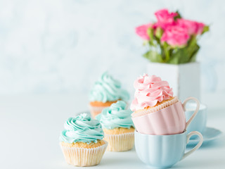 Blue pastel banner with decorated cupcakes, cup of coffe with milk and bouquet of pink roses.