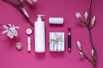 Beauty flat lay with gifts, cosmetics and magnolia flowers on the purple background. Top view concept 