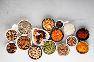 Composition with assortment of superfood products in bowls on gray background, top view