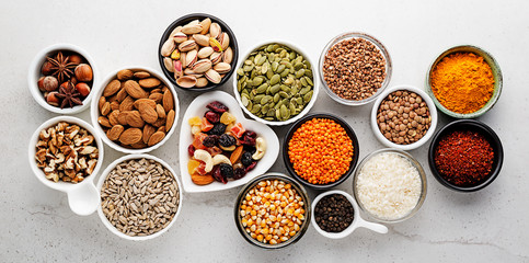 Composition with assortment of superfood products in bowls on gray background, top view