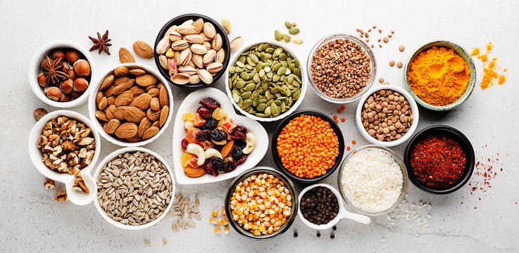 Composition with assortment of superfood products in bowls on gray background, top view