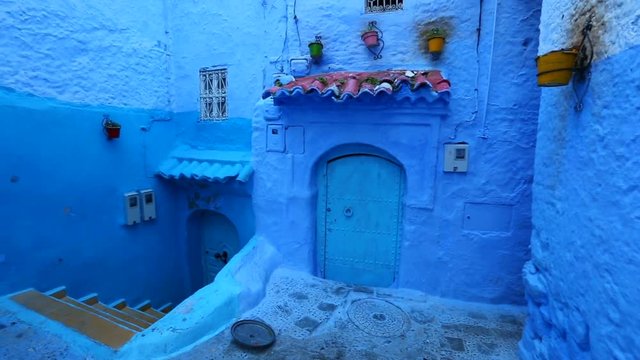 Panorama of traditional old blue street with color pots inside Medina of Chefchaouen, Morocco
