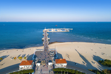 Sopot resort in Poland. Wooden pier (molo) with marina, yachts, beach, walking people, vacation infrastructure and promenade. Aerial view. - obrazy, fototapety, plakaty