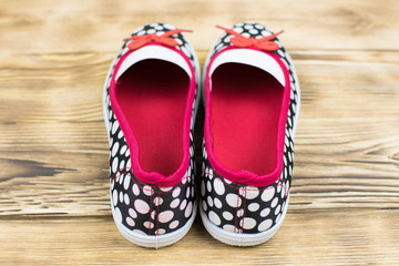 teenage textile shoes black in white polka dots, on a green wooden surface