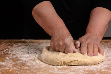 An old woman's grandmother is kneading a dough for cooking bread