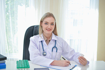 Doctor Concept. Smiling doctor posing in the office. Young doctor is wearing a stethoscope. medical staff on the hospital background. The doctors are happy to work.