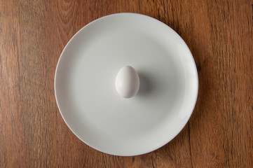 white egg on white dish on dark wood table
