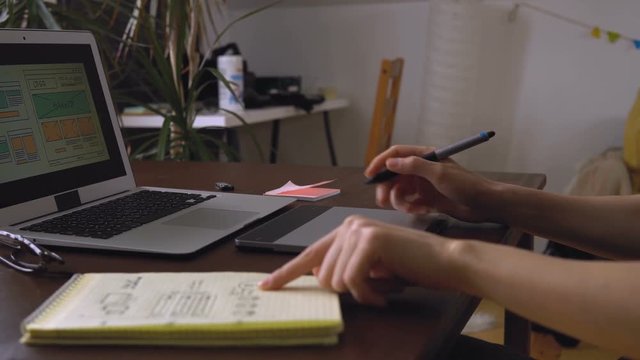 Web developer sitting at the table making a sketch of the future site. Working remotely from a home office.
