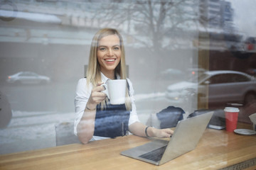 A girl is working at a laptop in a coffee cafe