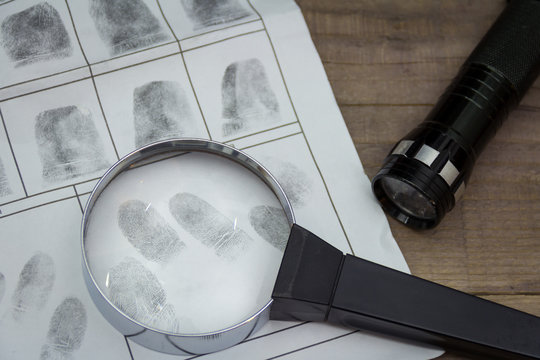 Fingerprints on paper with a magnifying glass. Flashlight in the background