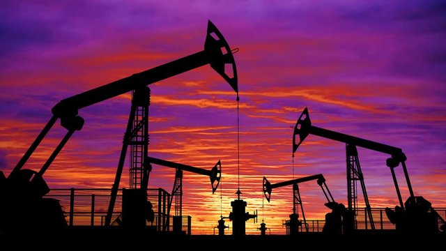 Oil pumpjacks against pink colorful cloudscape, seamless loop