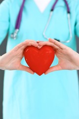 Female doctor with stethoscope holding heart in her arms. Healthcare and cardiology concept in medicine