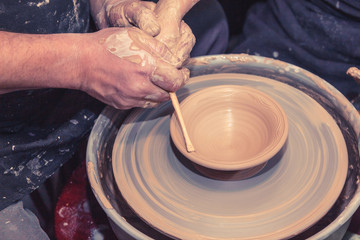 Senior potter teaching a little girl the art of pottery. Child working with clay, Creating ceramic pot on sculpting wheel. Concept of mentorship, generations. Arts lessons, pottery workshop for child