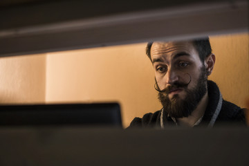 Modern, Expressive Bearded Office Clerk with Mustages Working with Notebook at Office