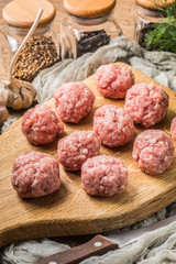 Raw meatballs on the wooden cutting board.