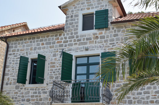 Coastal villa facade with green open wooden jalousies in summertime