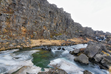 Perfectly pure glacial water flows down a stream through volcanic rocks in Iceland