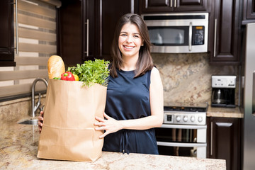 Woman in kitchen with grocery shopping bag