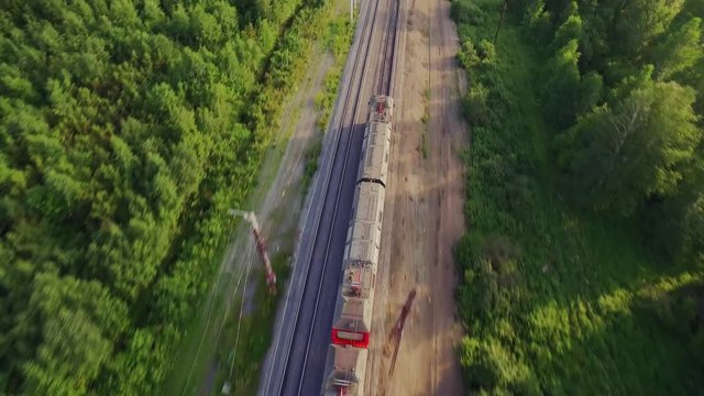 Electric locomotive  is going Fast by two-sided railways at summer sunny day. Aerial dynamic cinematic top view