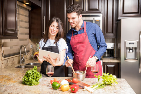 Latin couple using digital tablet in the kitchen for cooking