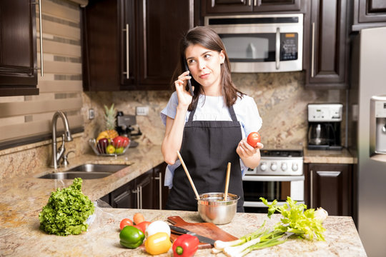 Woman using phone while cooking in kitchen